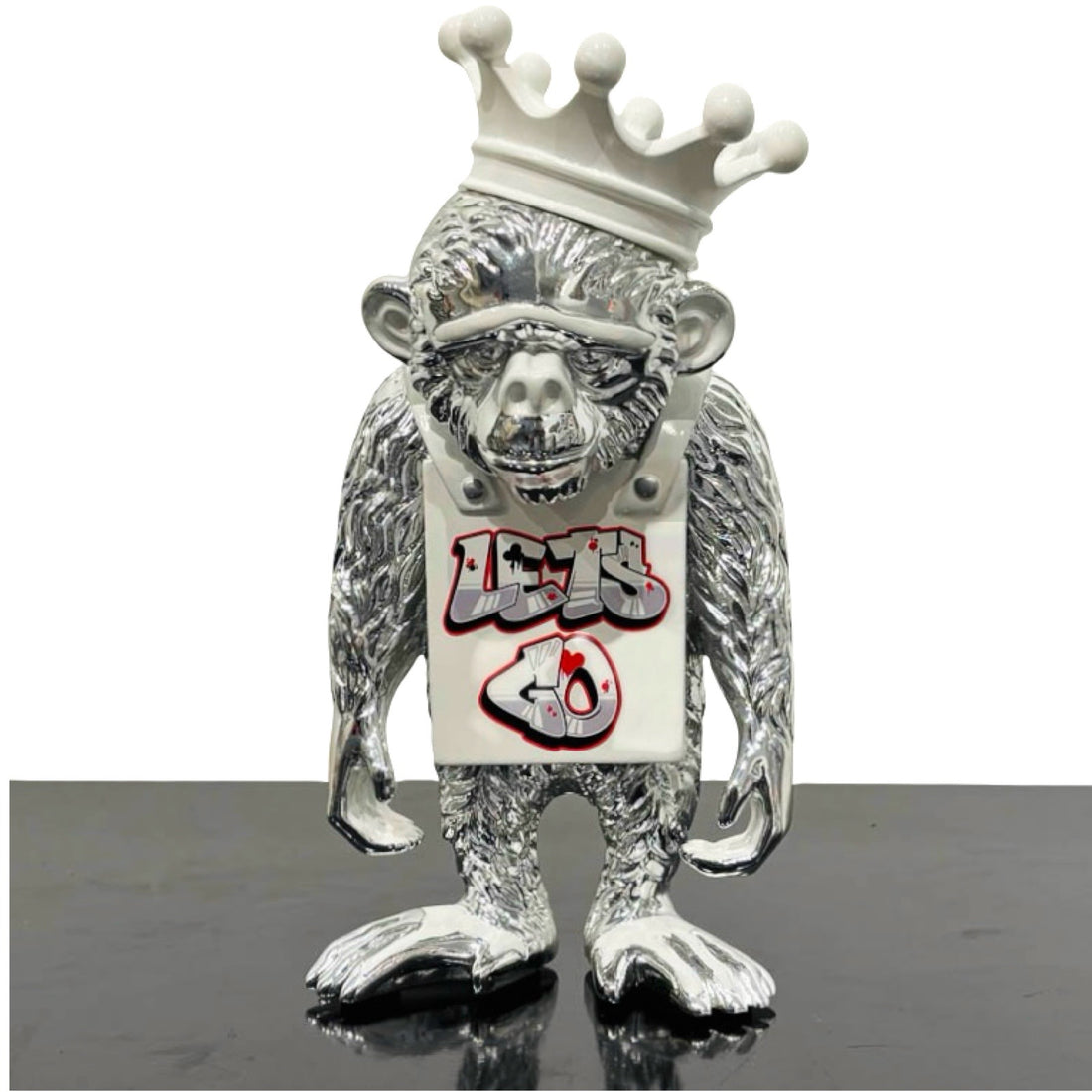 Sculpture of an silver monkey with white Lets Go sign and crown