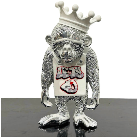 Sculpture of an silver monkey with white Lets Go sign and crown